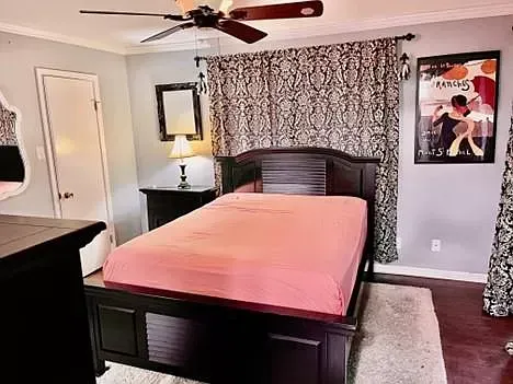 A bedroom with a bed , dresser , mirror and ceiling fan.