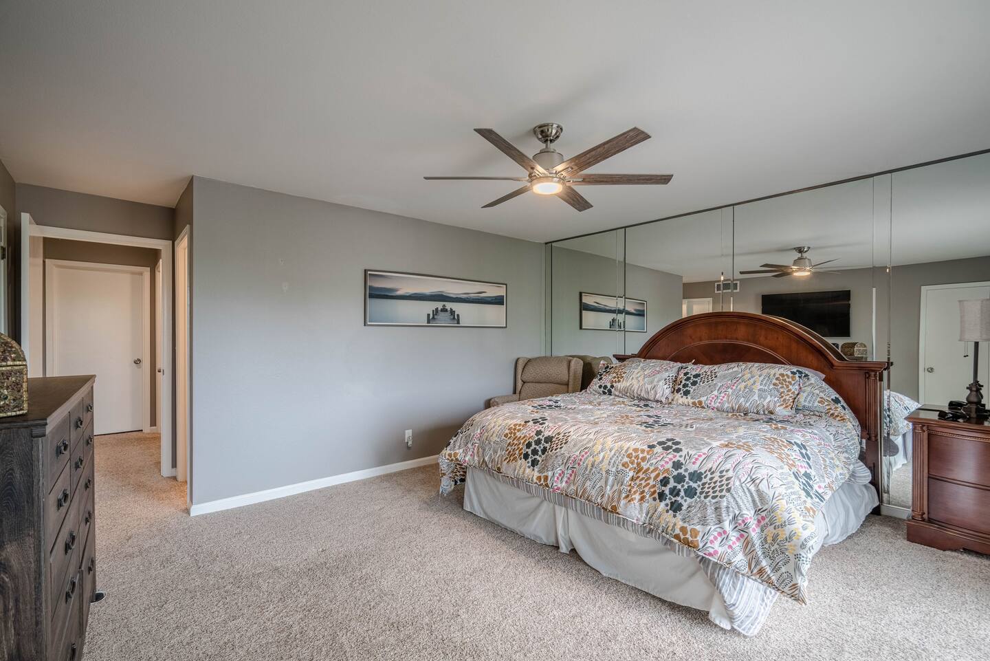 A bedroom with a large bed and a ceiling fan.