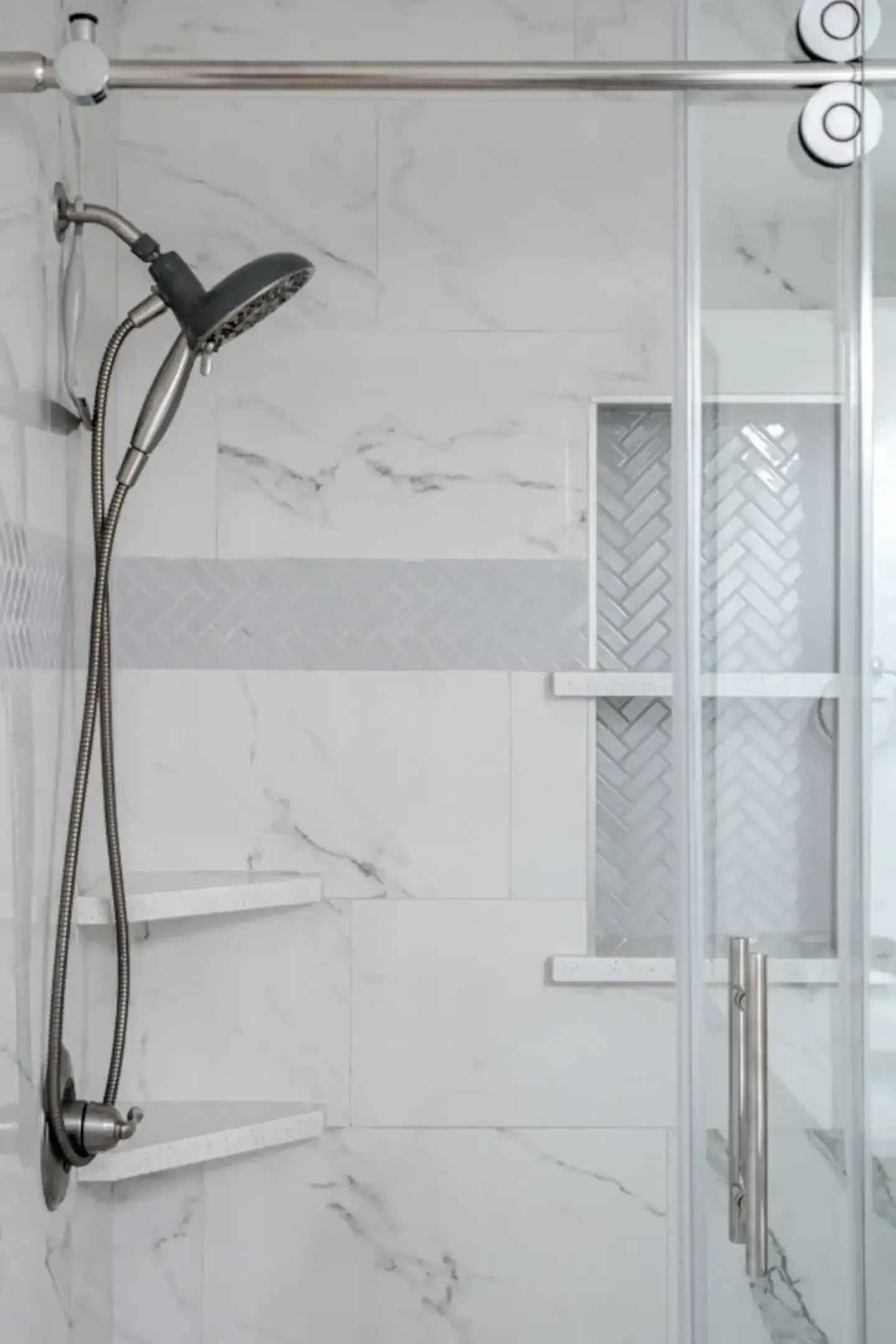 A shower with a sliding glass door and a shower head.
