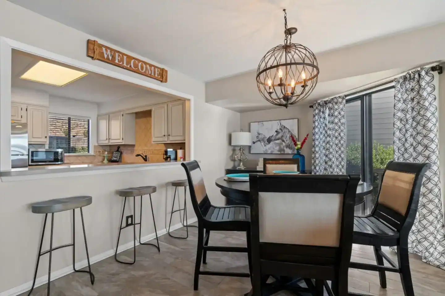 A dining room with a table and chairs and a sign that says welcome.