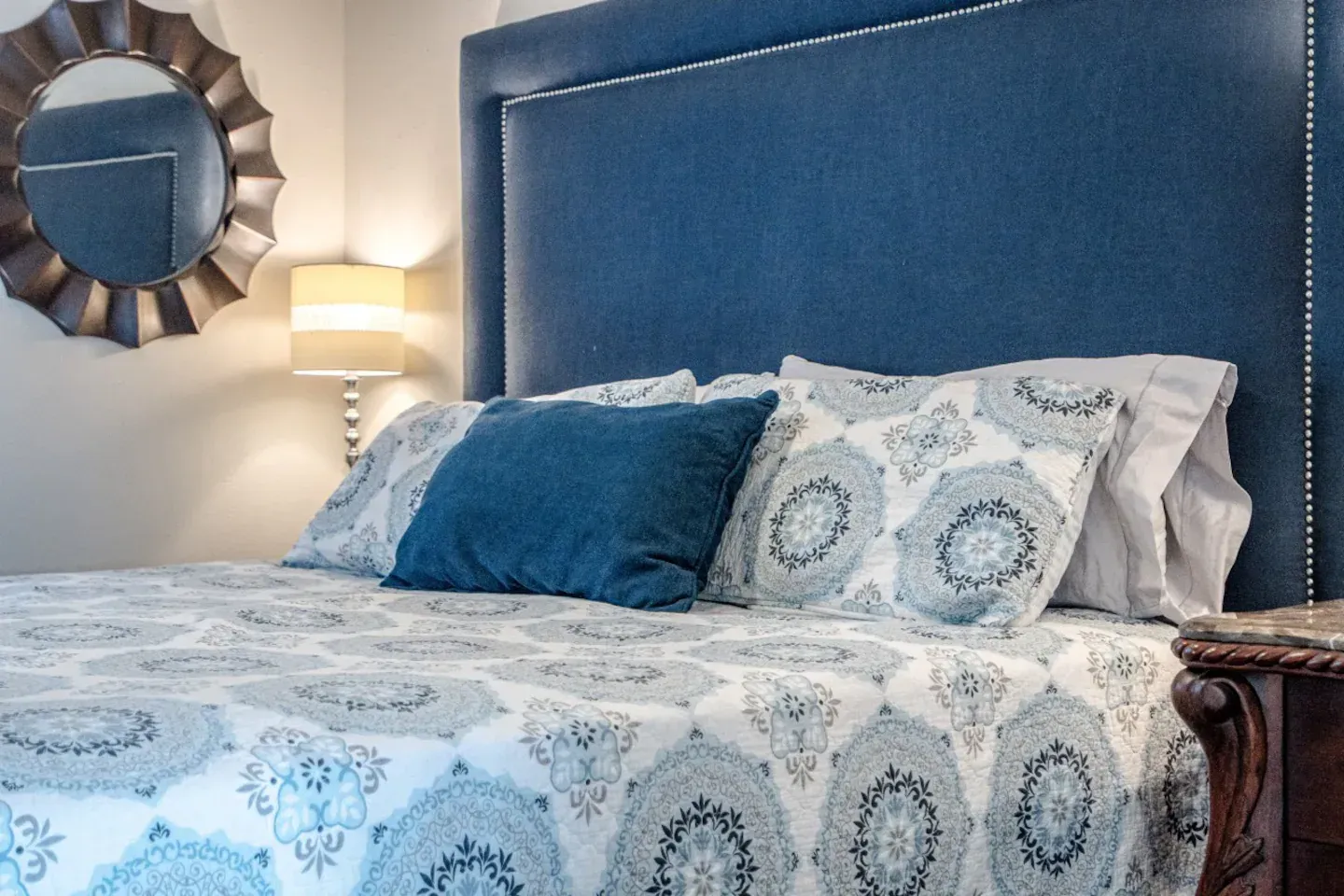 A bed with a blue headboard and pillows in a bedroom