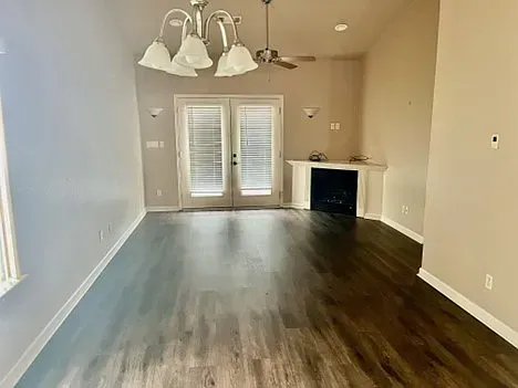 An empty living room with hardwood floors and a fireplace.