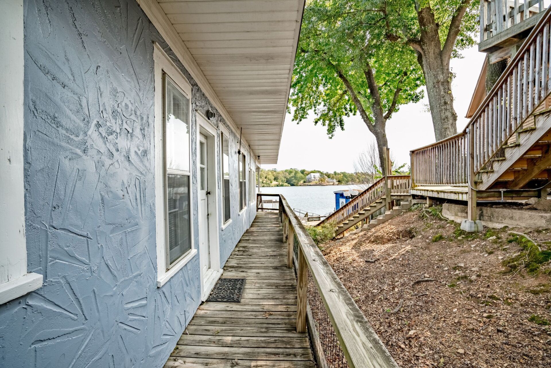A blue building with a wooden walkway leading to a lake.