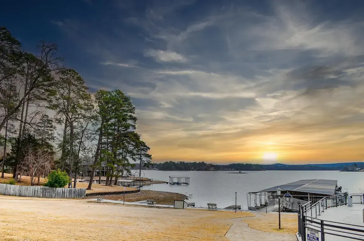 The sun is setting over a lake with a dock in the foreground.