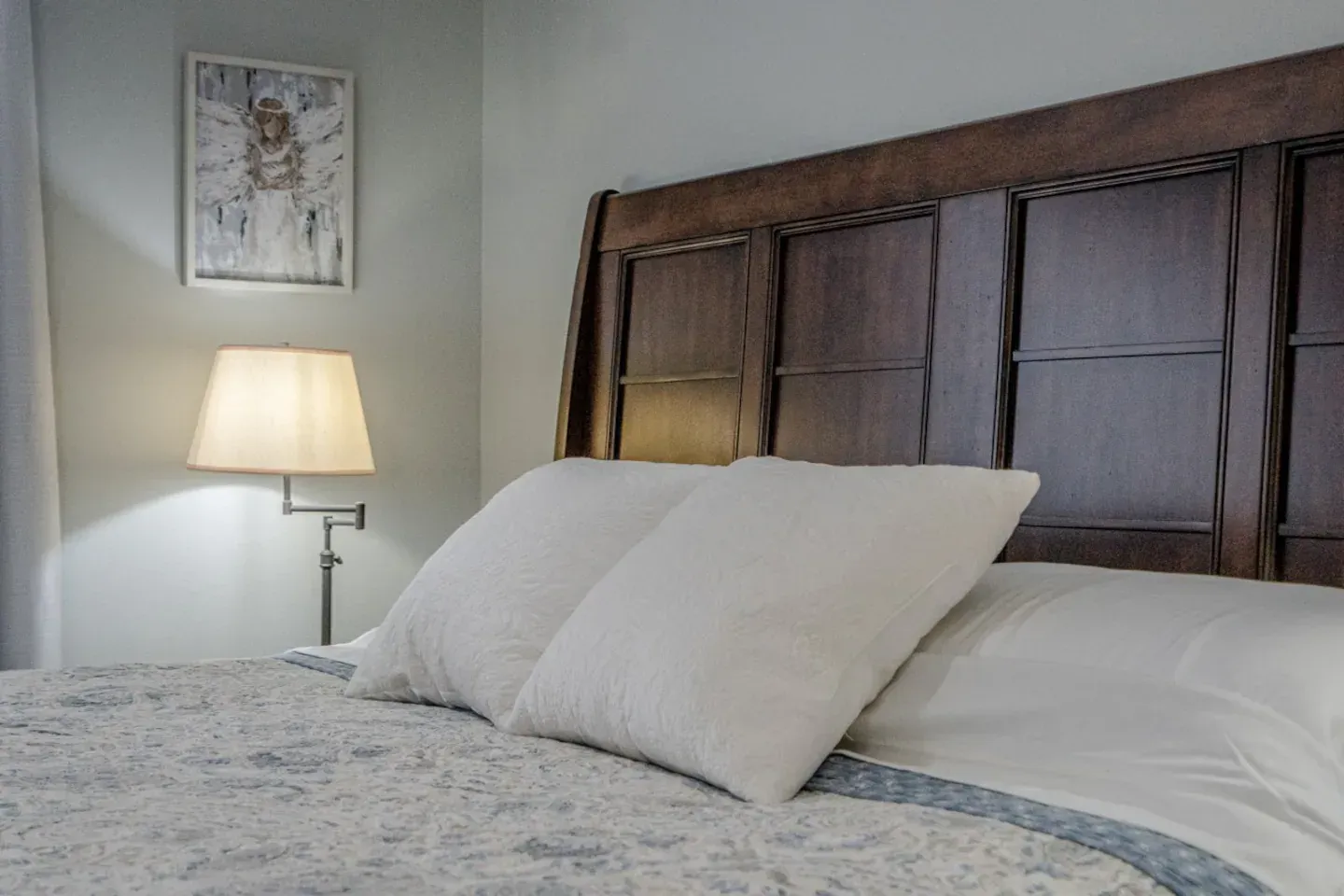 A bedroom with a bed , lamp , and picture on the wall.