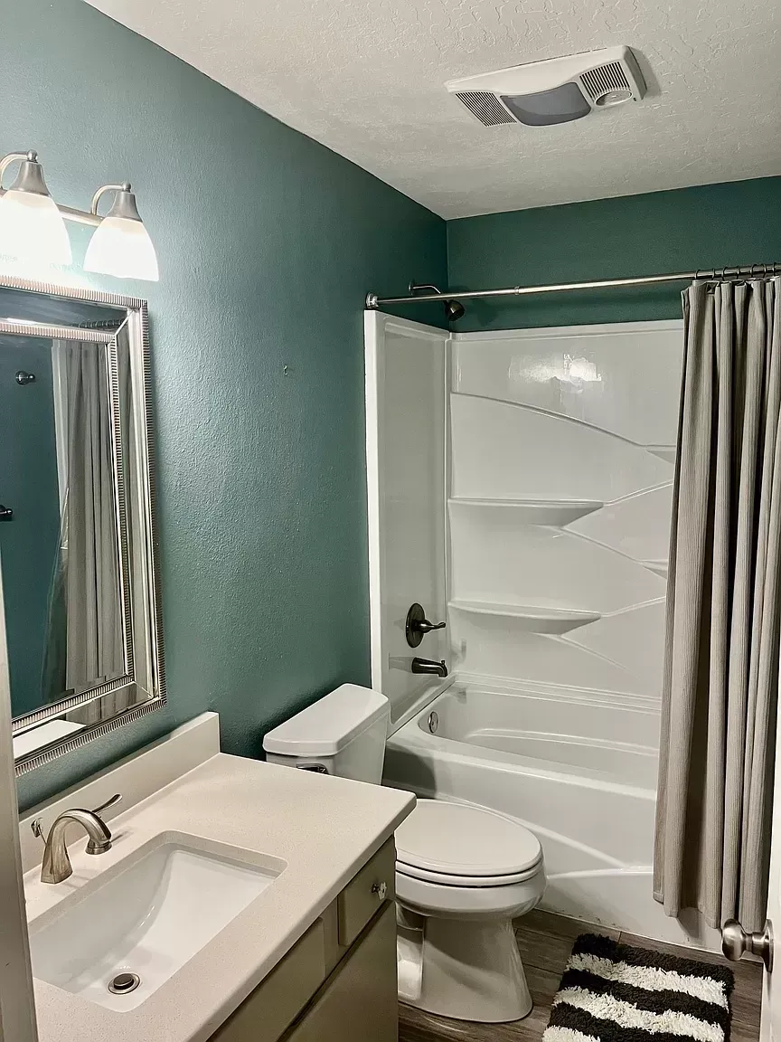 A bathroom with a sink , toilet , tub and mirror.