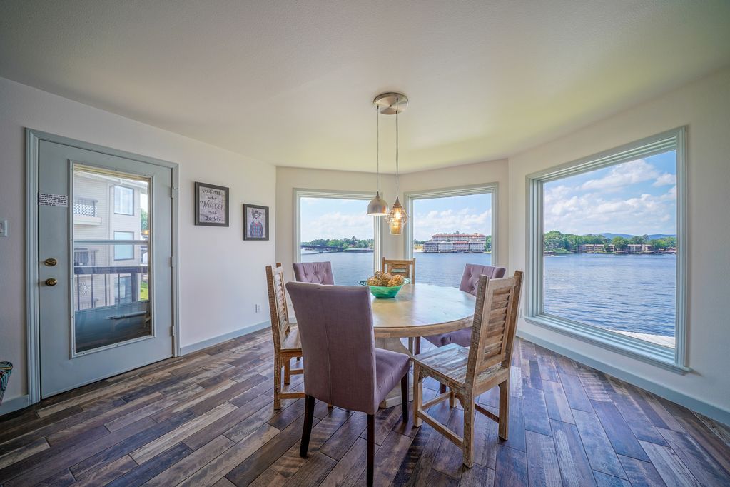 A dining room with a table and chairs overlooking a lake.