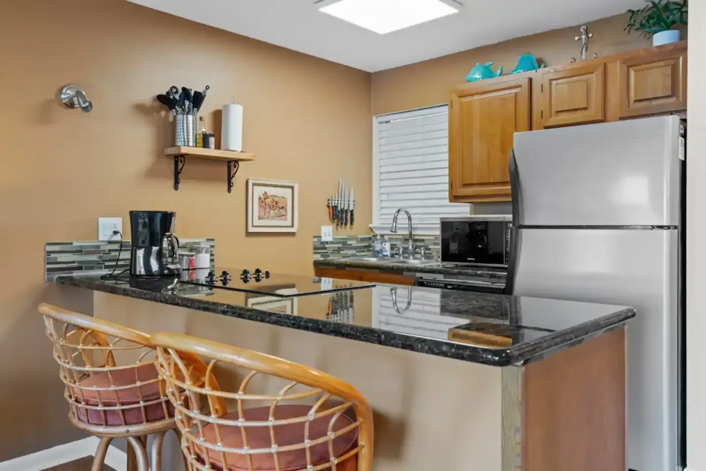A kitchen with a refrigerator , stove , sink , and bar.