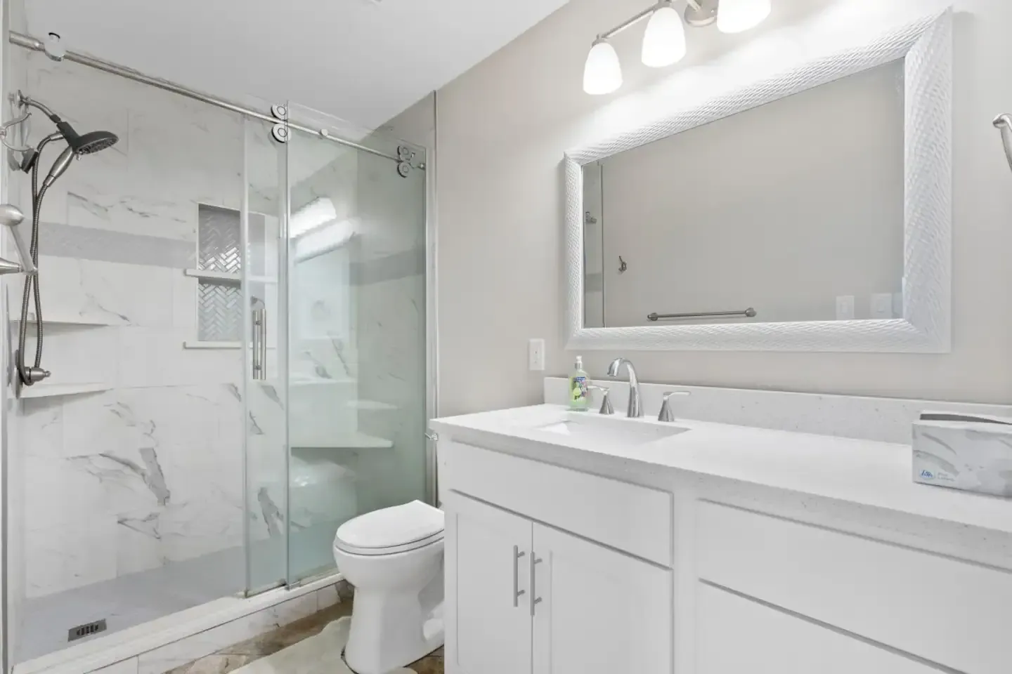 A bathroom with a toilet , sink , mirror and shower.