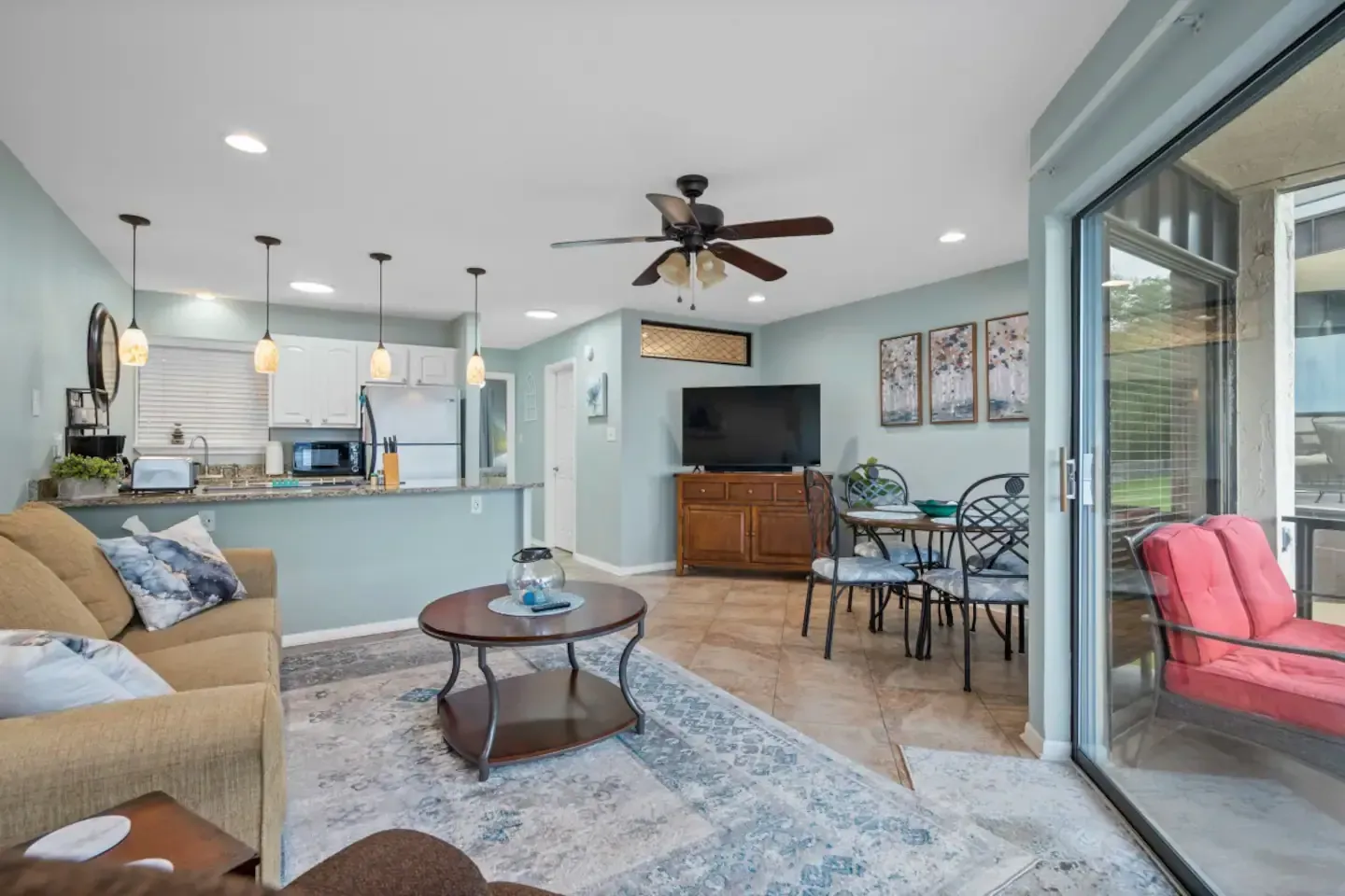 A living room with a couch , table , chairs and a ceiling fan.