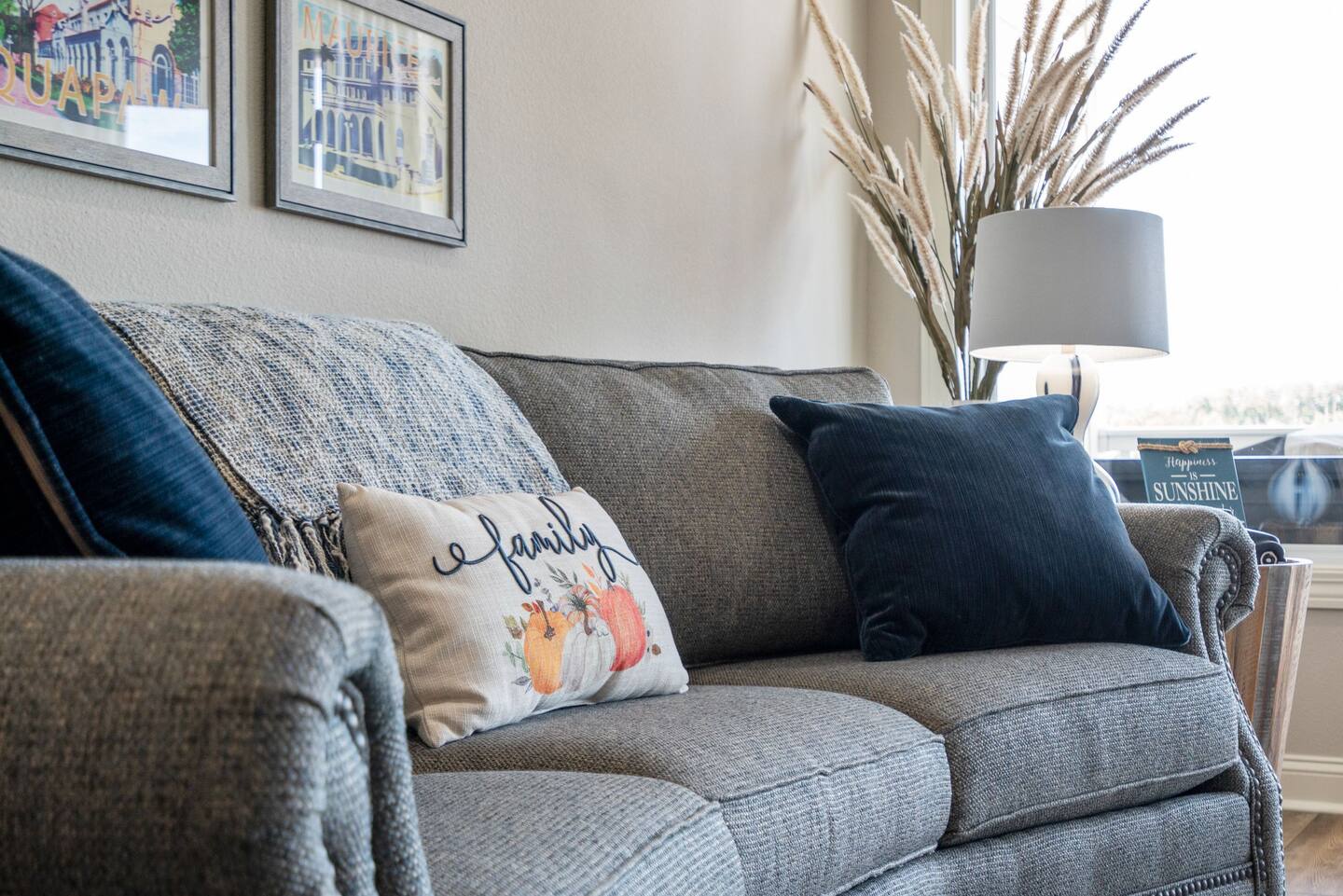 A couch with a pillow that says `` family '' is in a living room.