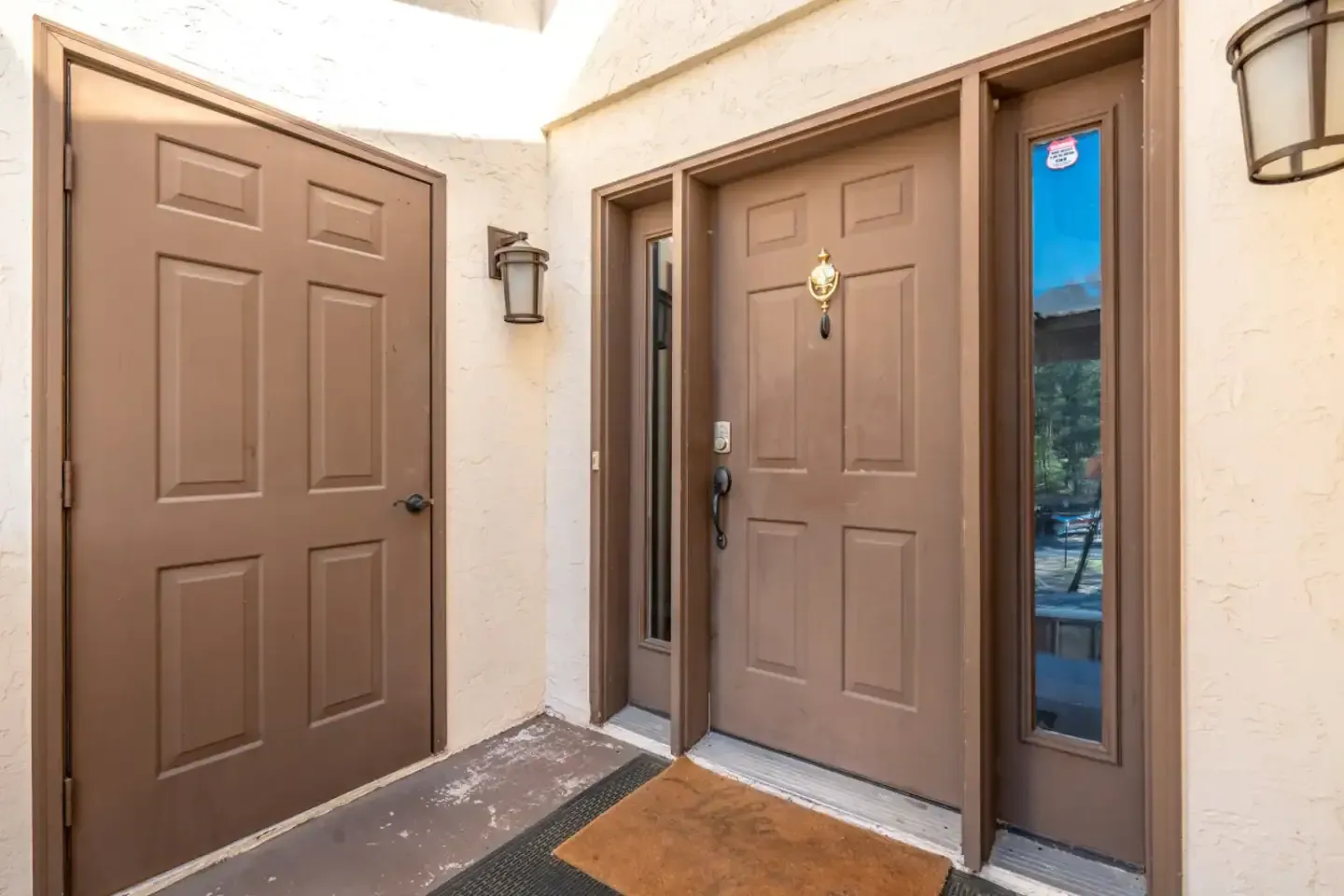 The front door of a house with two brown doors and a door mat.