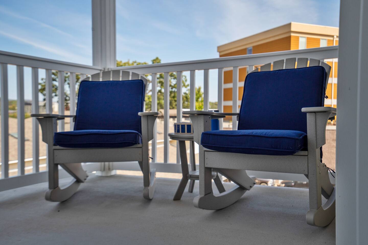 Two rocking chairs with blue cushions are on a porch.