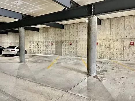 A parking garage with cars parked in it and a concrete wall.