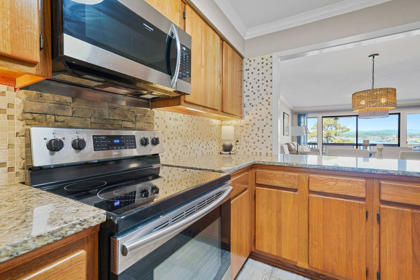 A kitchen with a stove , microwave , and granite counter tops.