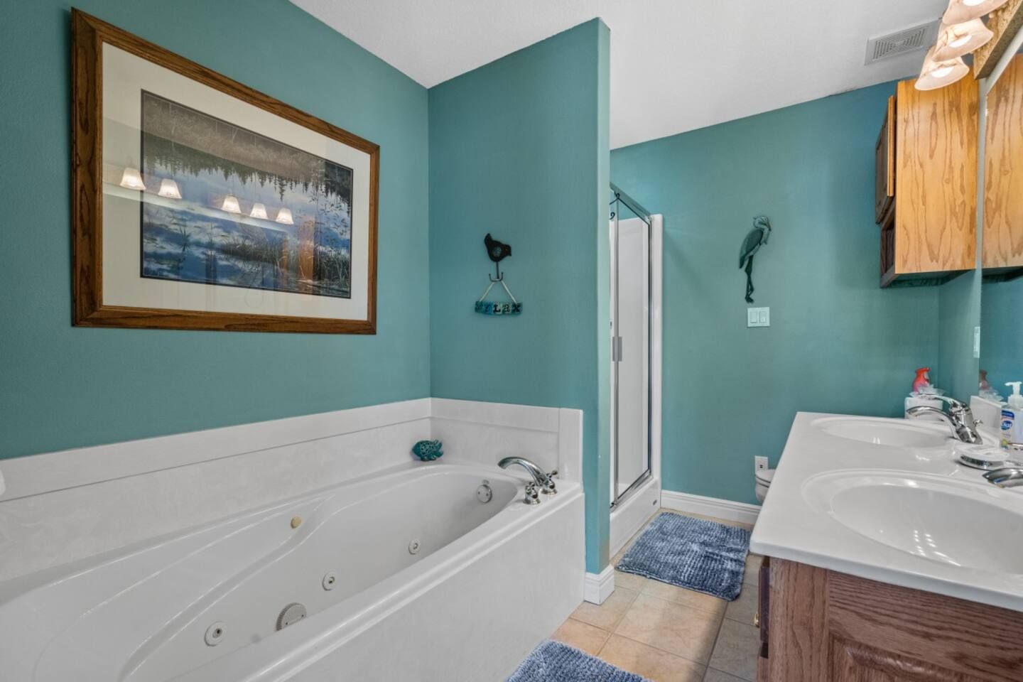 A bathroom with a jacuzzi tub , sinks , and a picture on the wall.