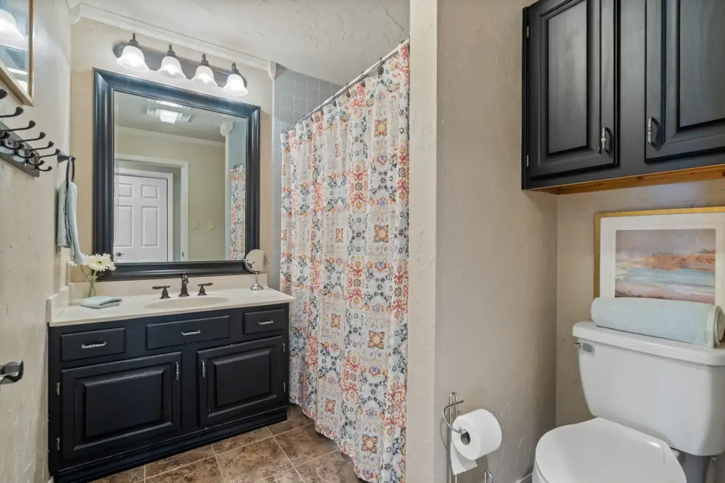 A bathroom with a toilet , sink , mirror and shower curtain.