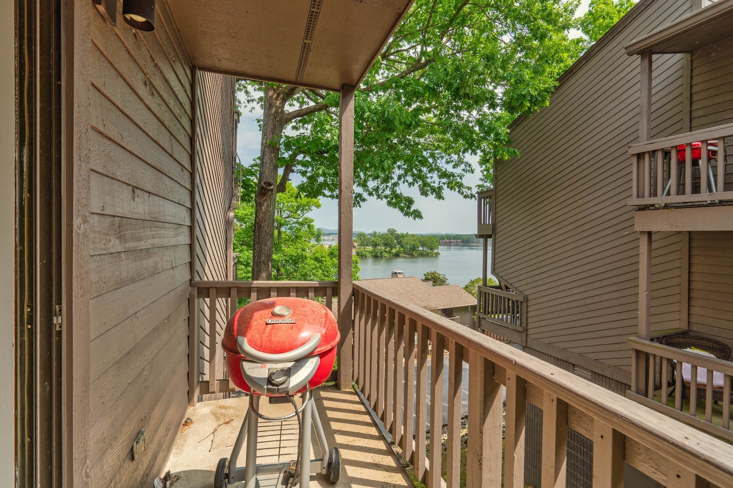 A balcony with a grill and a view of a lake.