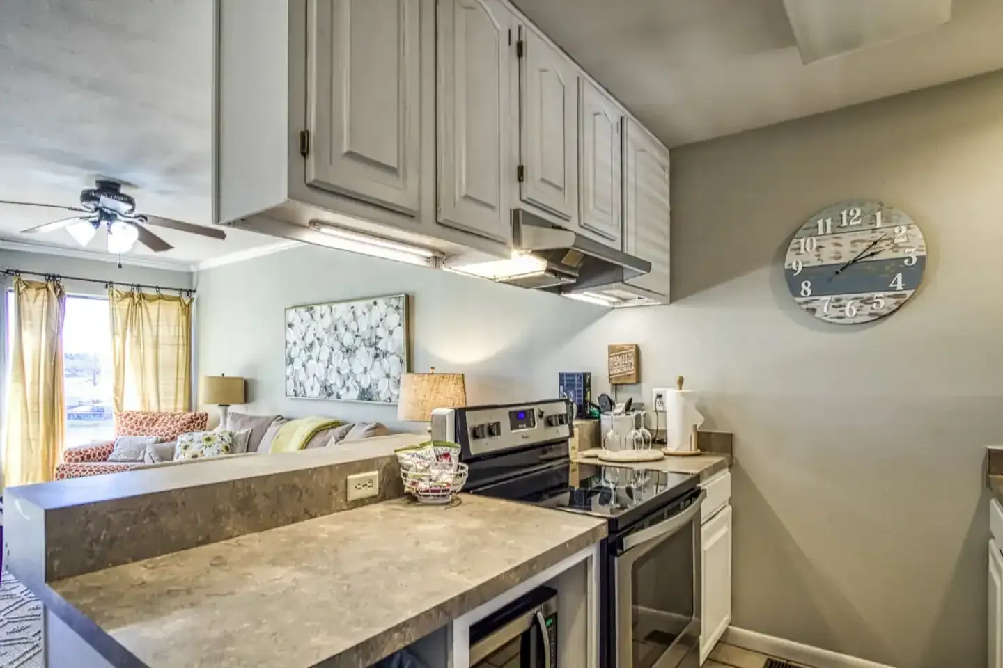 A kitchen with a stove , microwave , refrigerator and cabinets.