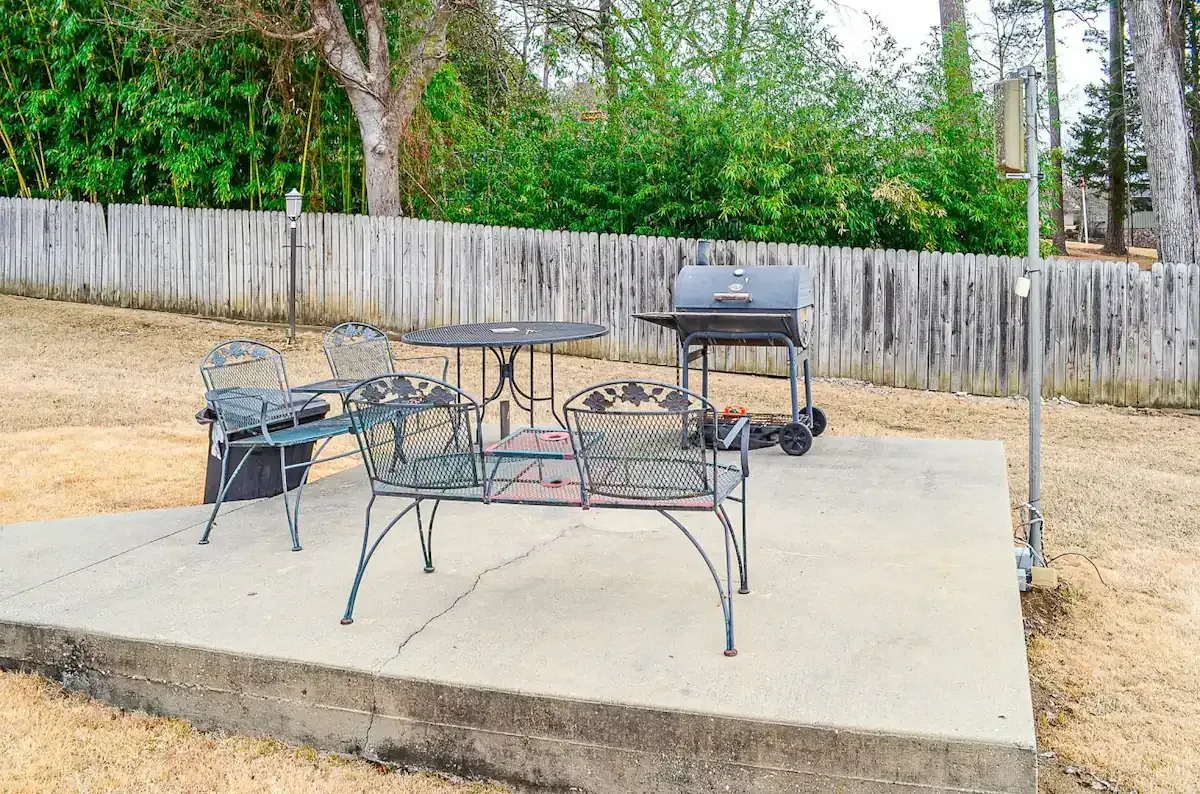 A patio with a table and chairs and a grill.