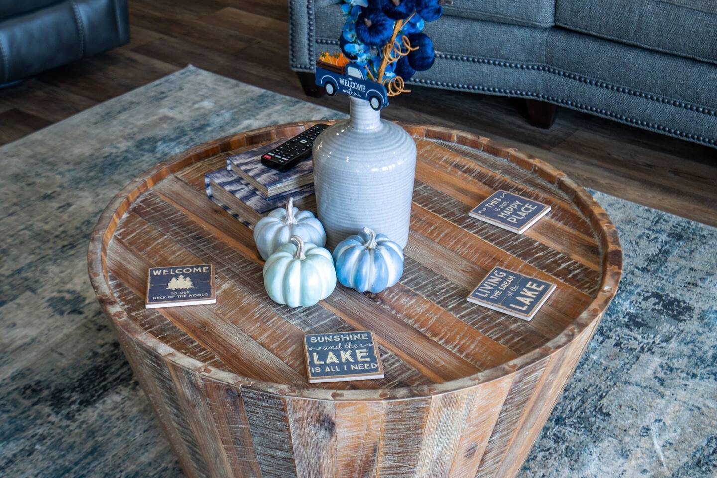 A wooden coffee table with pumpkins and a vase on it in a living room.