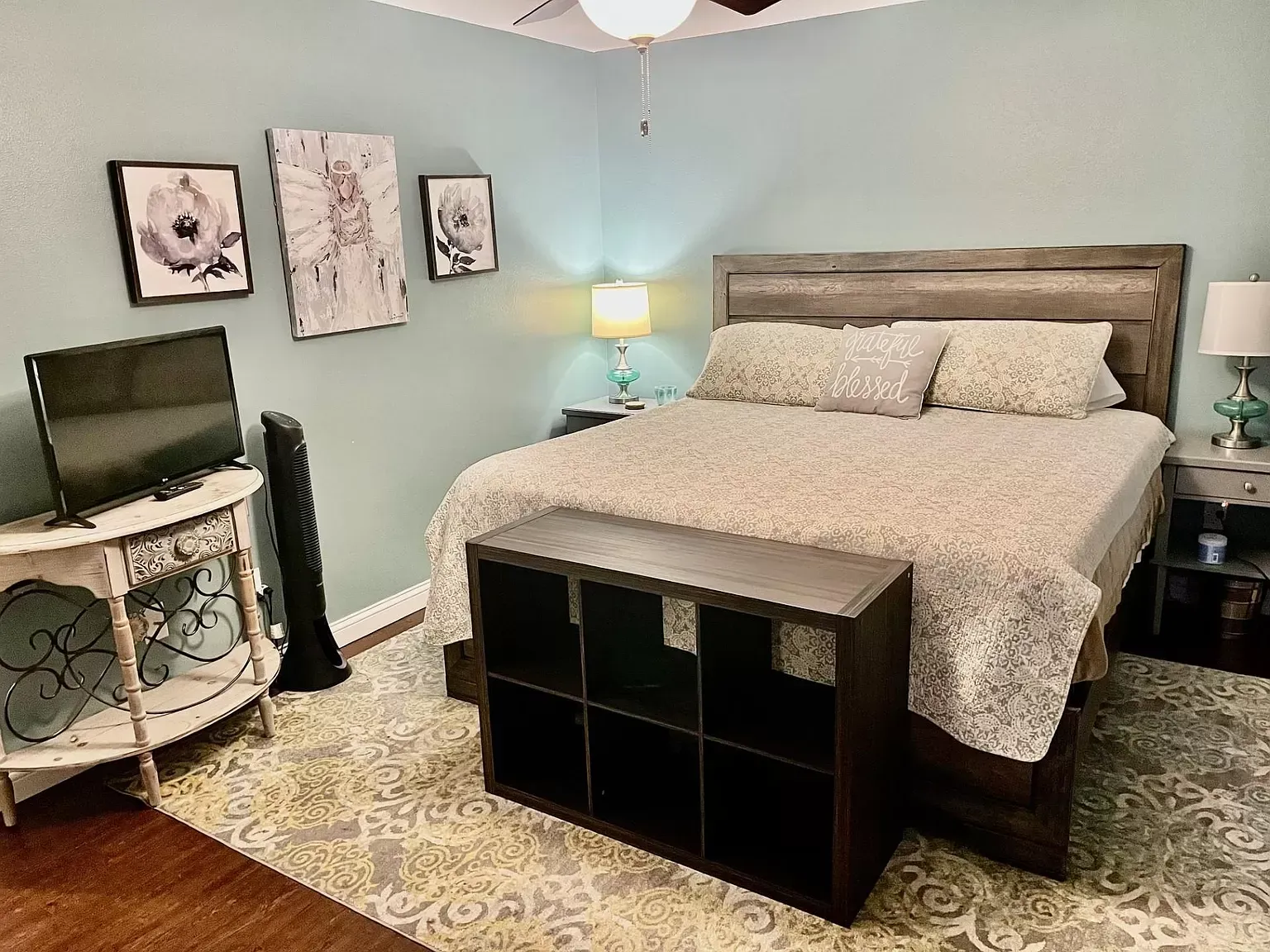 A bedroom with a king size bed , a television , a nightstand , and a bench.