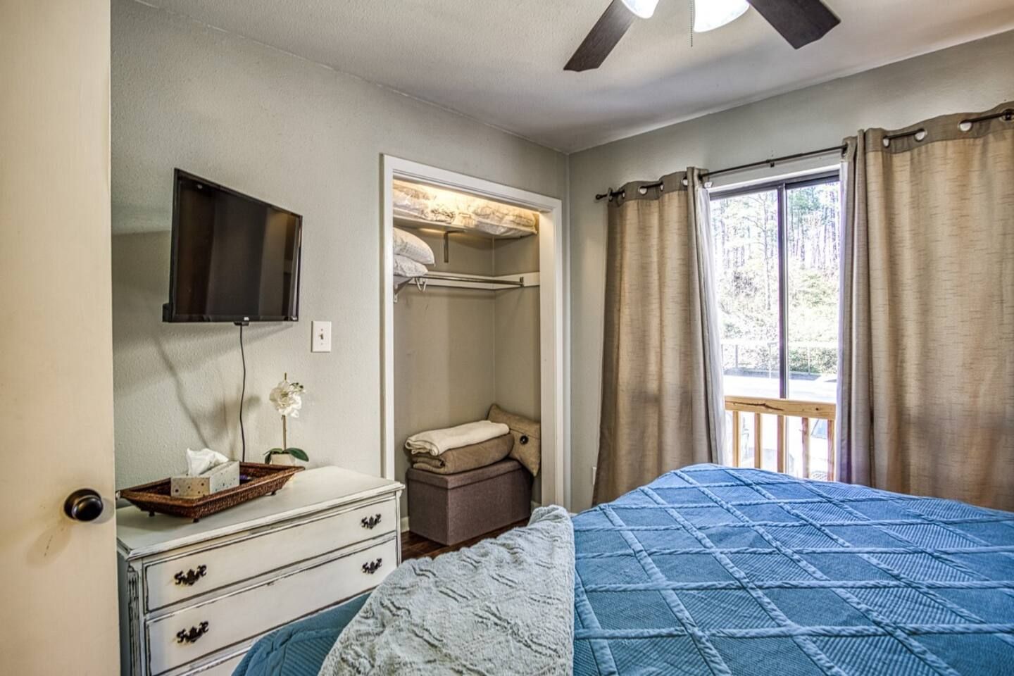 A bedroom with a bed , dresser , television and closet.