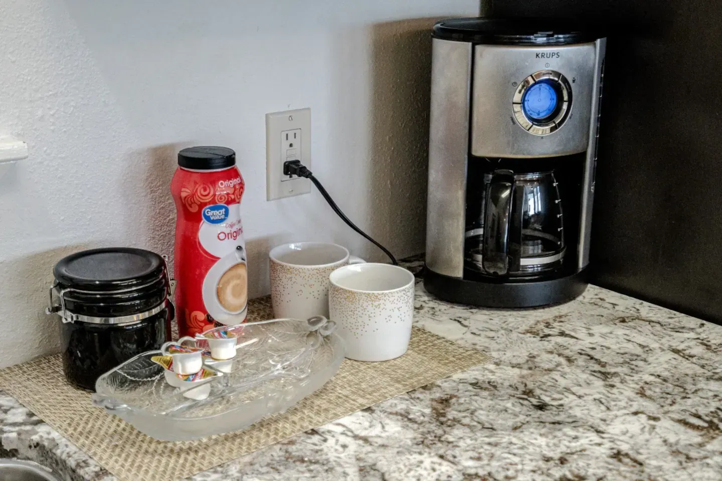 A coffee maker is sitting on a counter next to a bowl of coffee.
