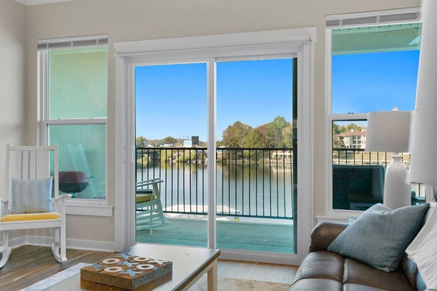 A living room with a couch , table , chair and sliding glass doors leading to a balcony overlooking a lake