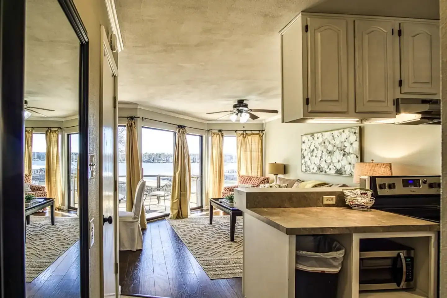 A kitchen with a stove , sink , cabinets and a mirror.