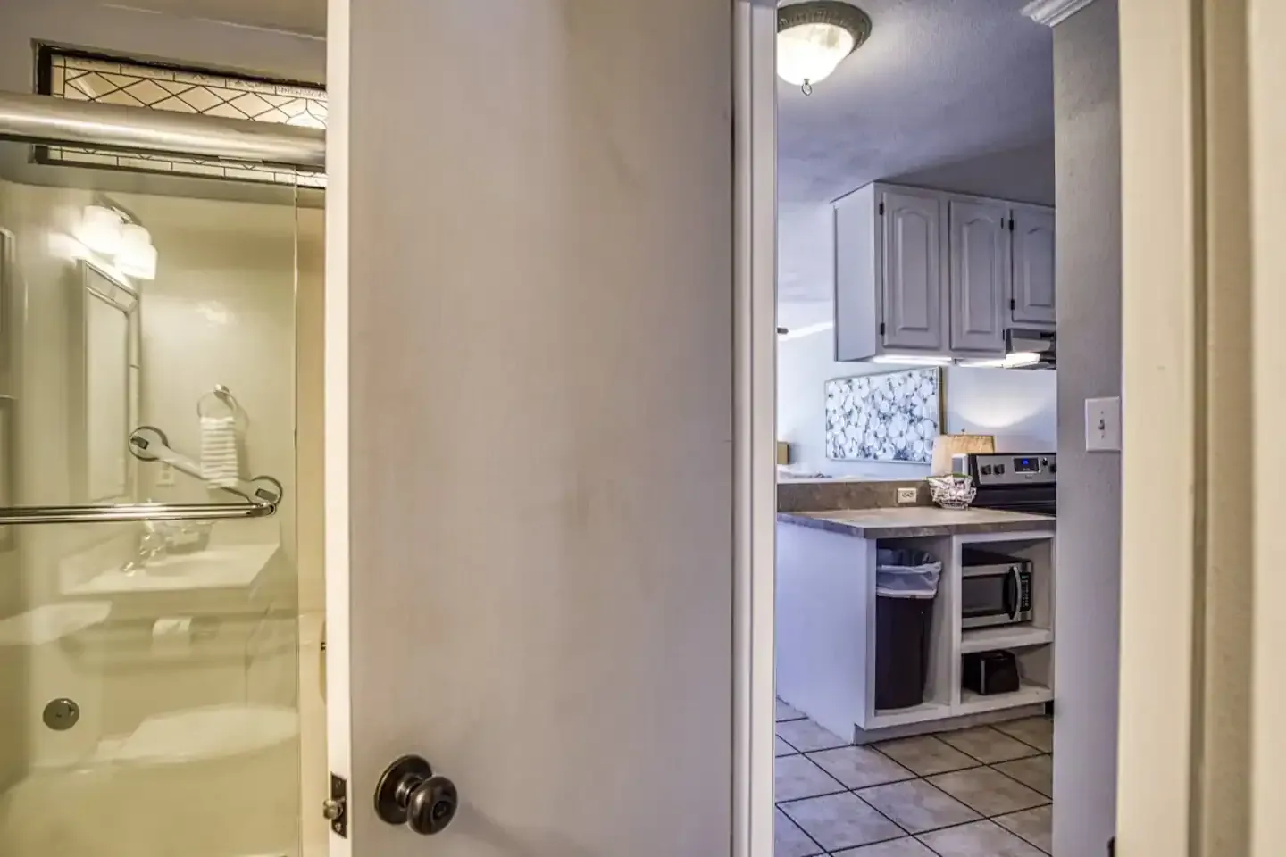 A bathroom with a tub and a door leading to a kitchen.