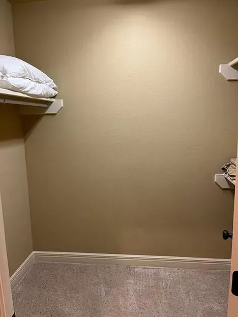 A walk in closet with shelves and a door.