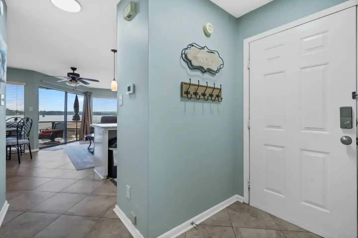 A hallway in a house with a white door and a ceiling fan.