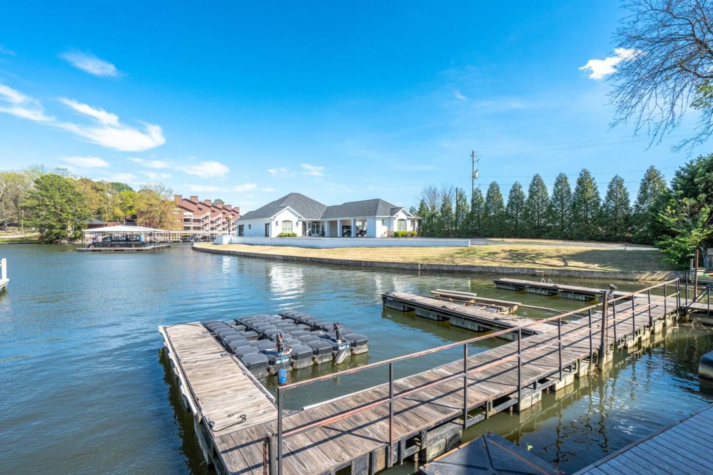 There is a dock in the middle of a lake with a house in the background.