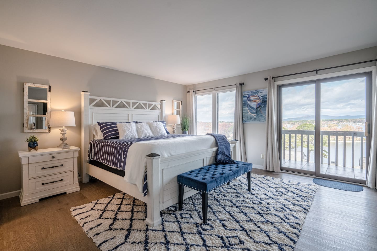 A bedroom with a king size bed , nightstand , bench and sliding glass doors.