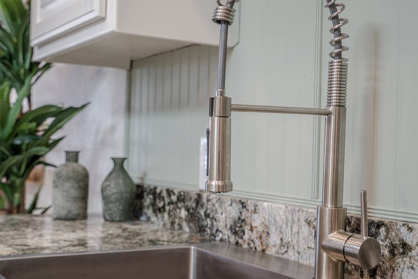 A kitchen sink with a faucet and vases on the counter.