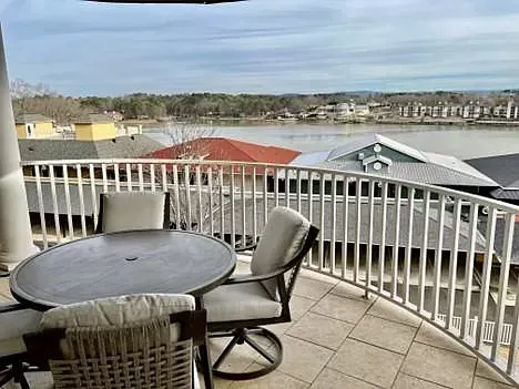 A balcony with a table and chairs overlooking a lake.