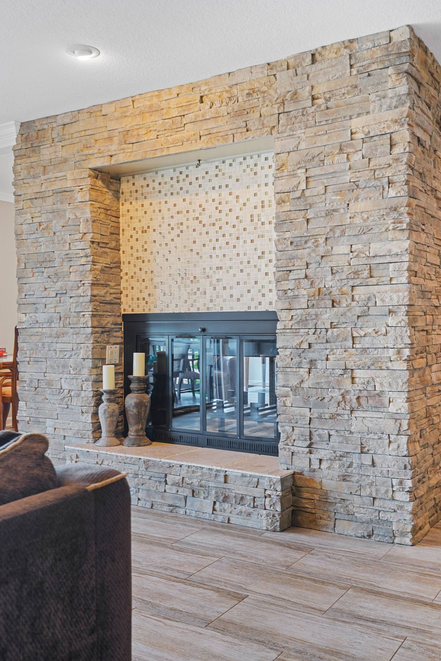 A living room with a large stone fireplace and a couch.
