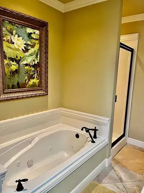 A bathroom with a jacuzzi tub and a painting on the wall above it.