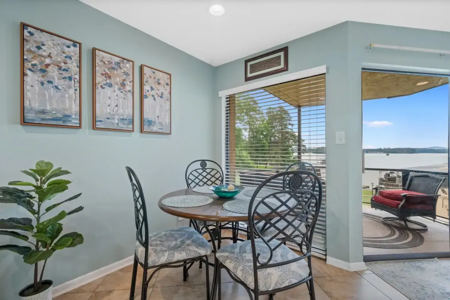 A dining room with a table and chairs and a potted plant.