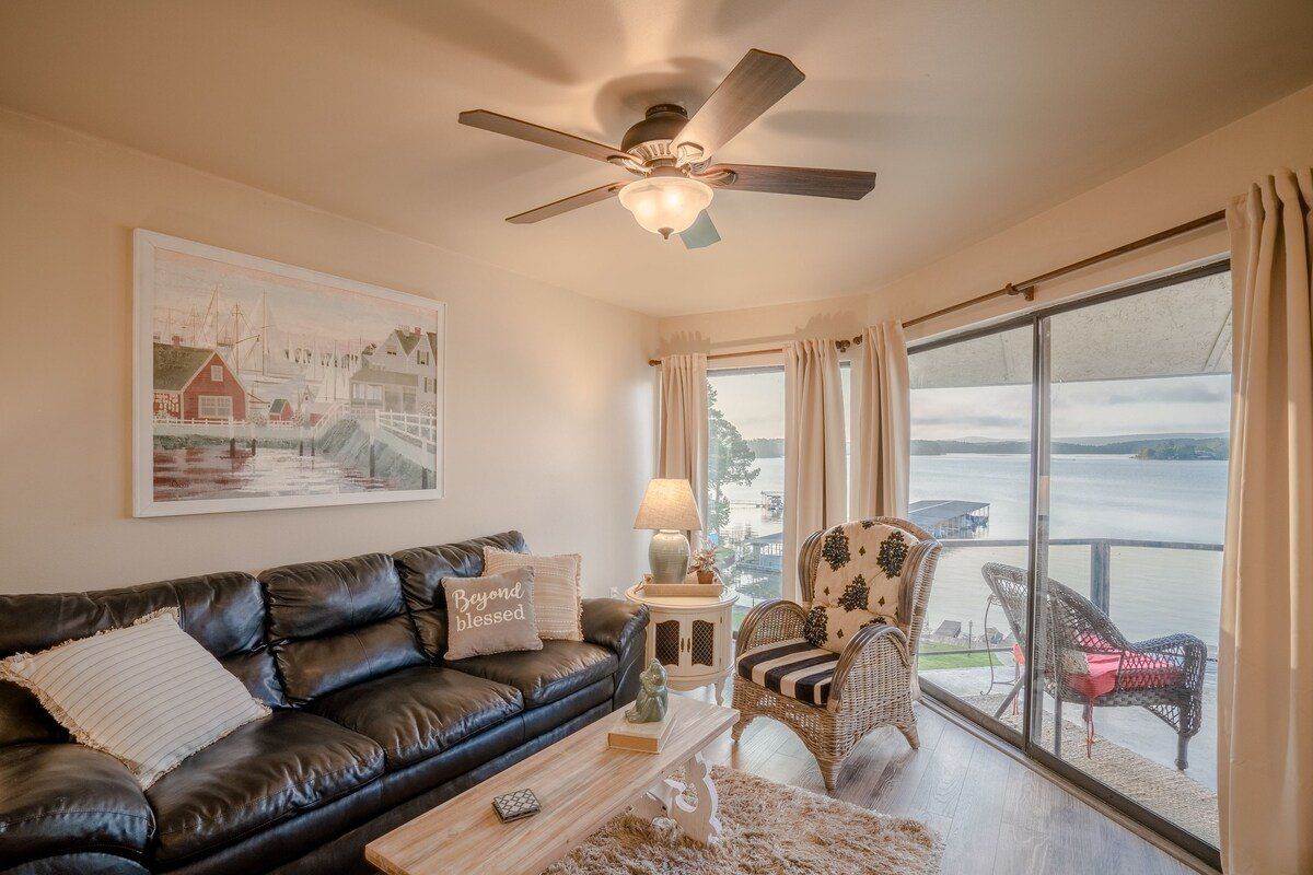 A living room with a couch , chair , table and ceiling fan.
