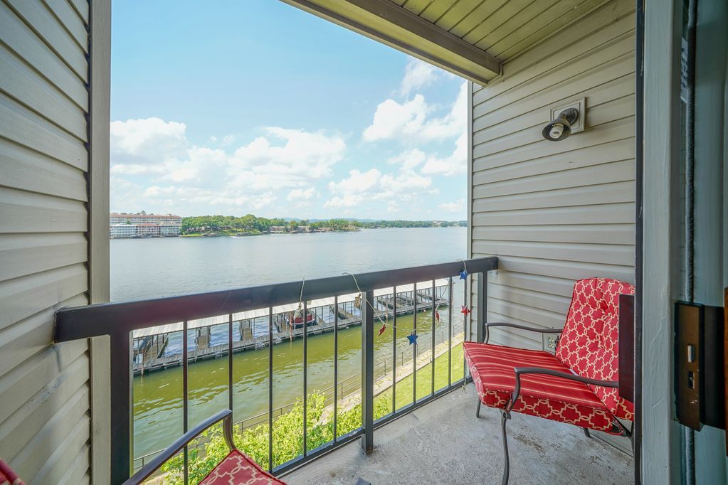 A balcony with a chair and a table overlooking a body of water.
