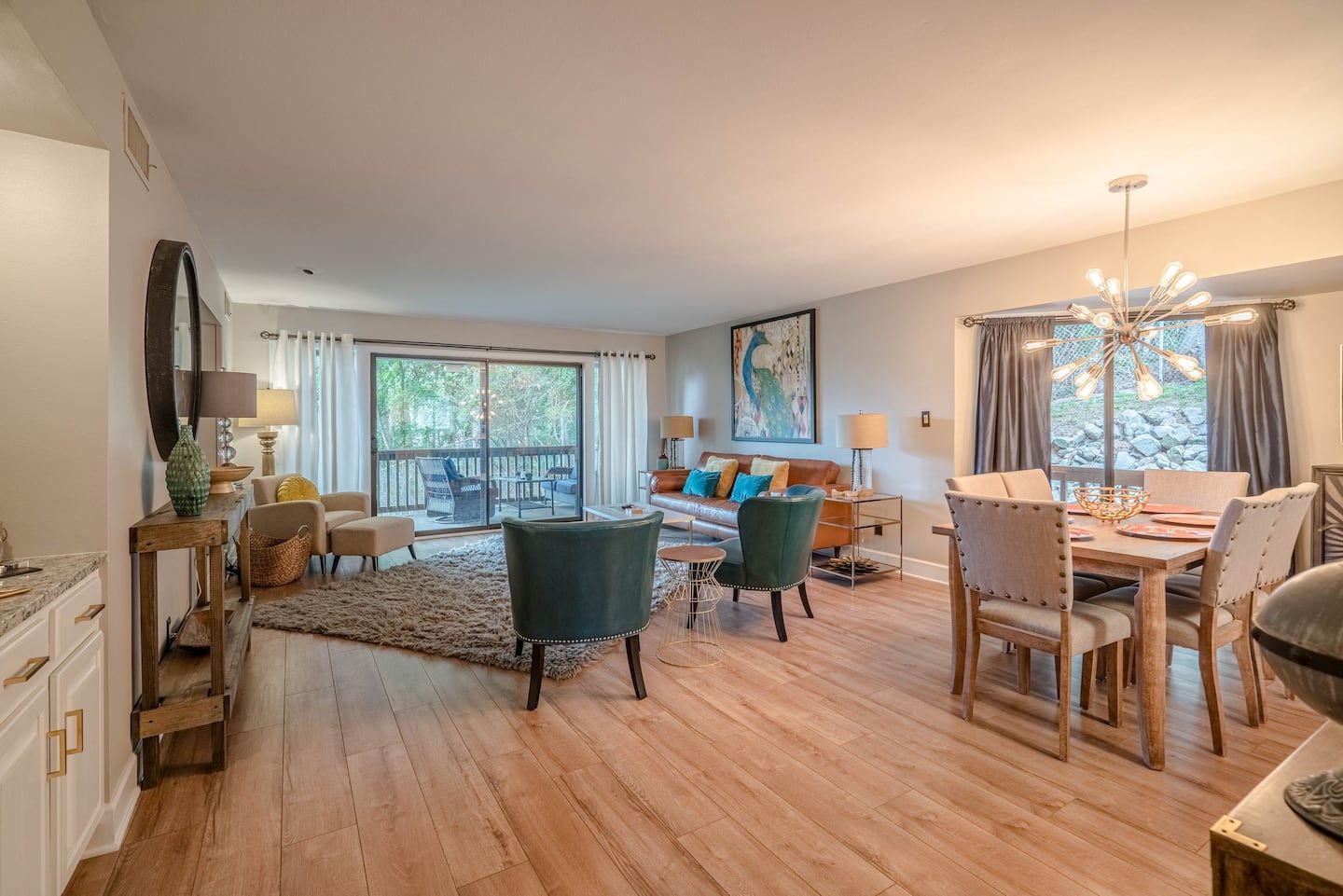 A living room with a dining table and chairs and a balcony.