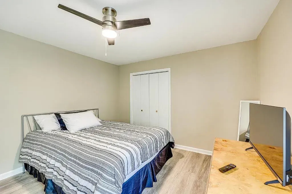 A bedroom with a bed , television and ceiling fan.