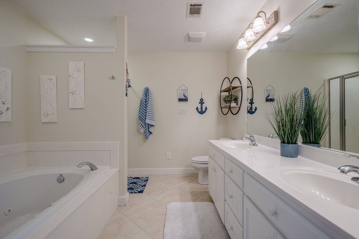 A bathroom with two sinks , a tub , a toilet and a mirror.