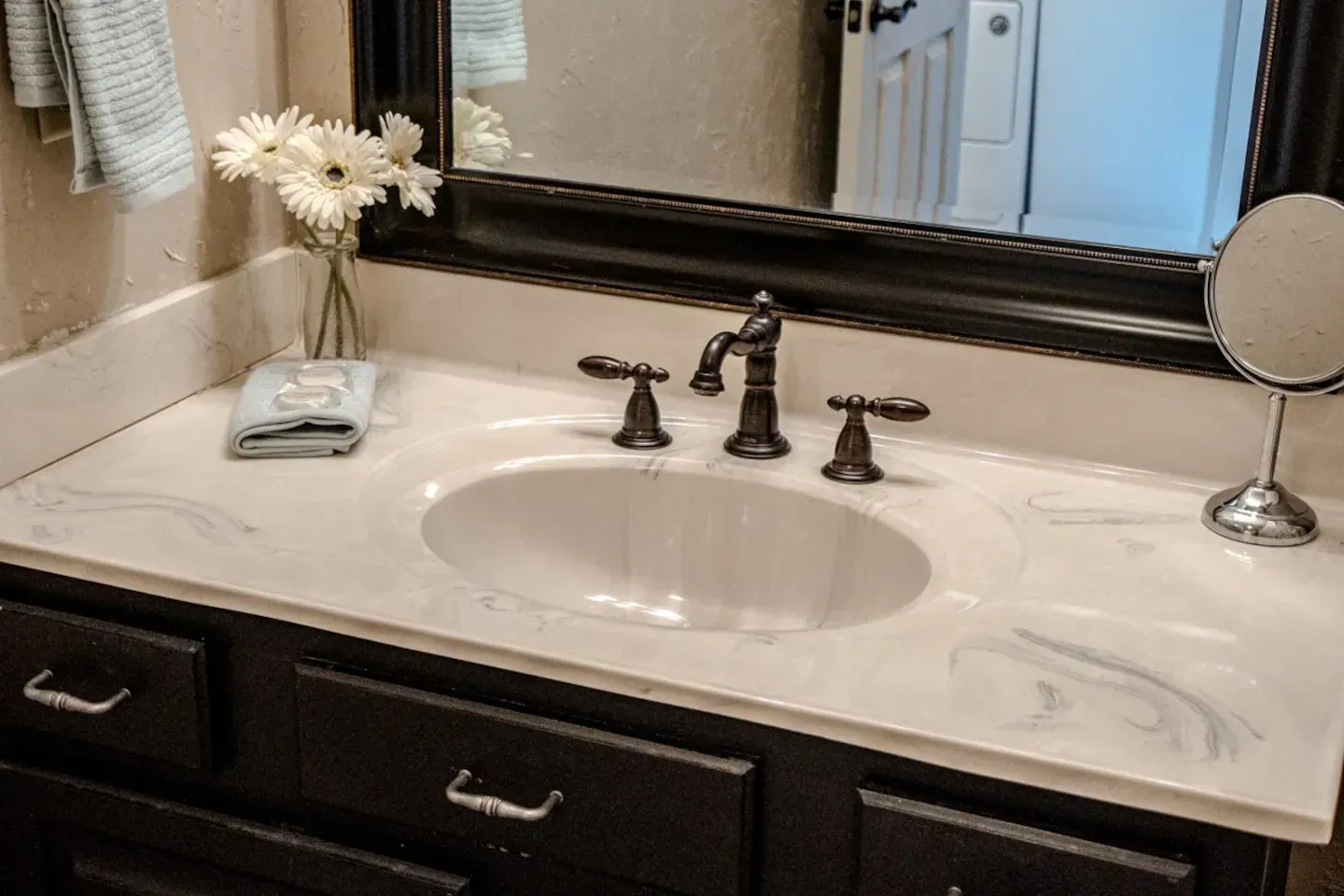 A bathroom sink with a mirror and a vase of flowers on it.