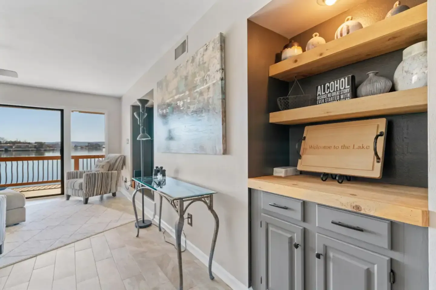 A living room with a table , chairs , shelves and a view of the water.