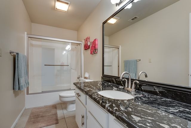 A bathroom with a sink , toilet , shower and mirror.