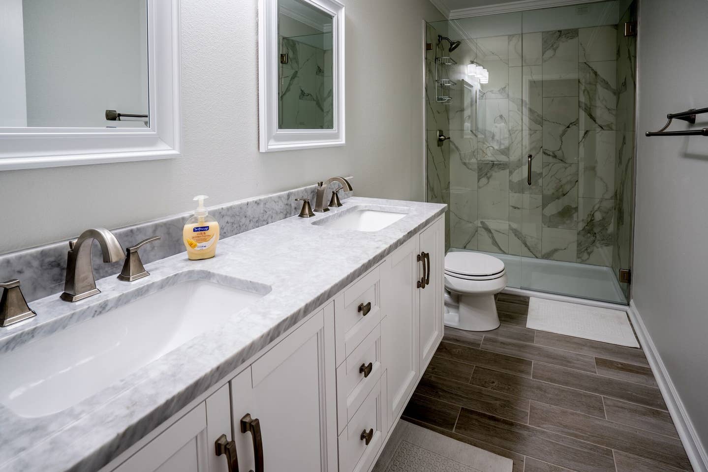 A bathroom with two sinks , a toilet , and a walk in shower.