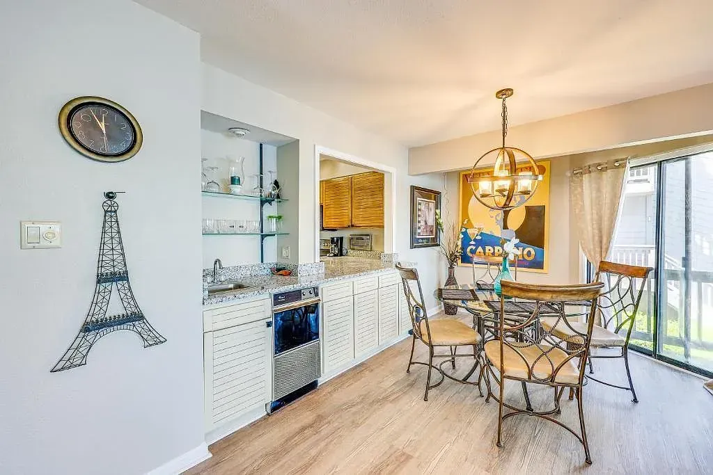 A dining room with a table and chairs and a clock on the wall.